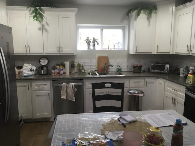 kitchen featuring a sink, freestanding refrigerator, white cabinetry, and dishwasher