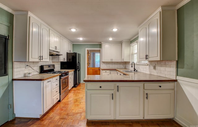 kitchen featuring stainless steel gas range, sink, white cabinetry, and kitchen peninsula