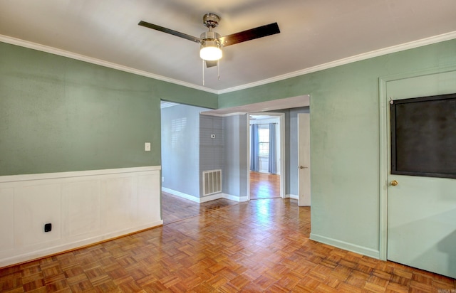 spare room with parquet flooring, ornamental molding, and ceiling fan