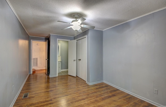 unfurnished bedroom featuring crown molding, a textured ceiling, dark wood-type flooring, and ceiling fan