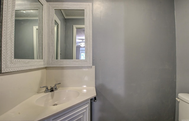 bathroom with vanity, toilet, and crown molding