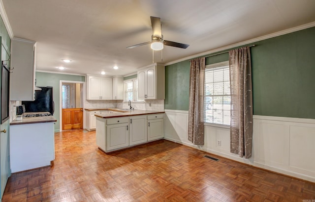 kitchen with kitchen peninsula, white cabinets, ceiling fan, and a wealth of natural light