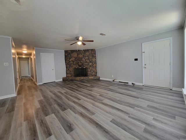 unfurnished living room with ceiling fan, a textured ceiling, light hardwood / wood-style flooring, and a fireplace