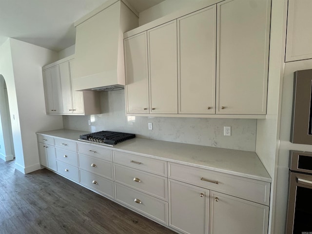 kitchen featuring appliances with stainless steel finishes, white cabinets, dark wood-type flooring, and backsplash