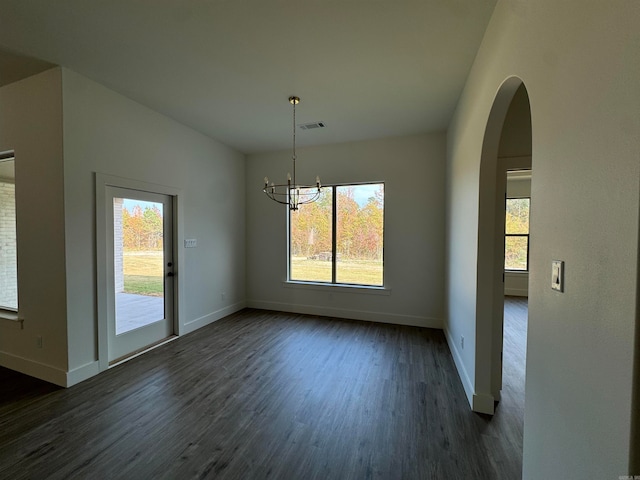 unfurnished dining area with a wealth of natural light, an inviting chandelier, and dark hardwood / wood-style flooring