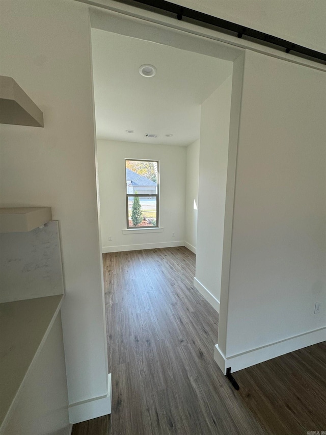 hall with a barn door and hardwood / wood-style floors