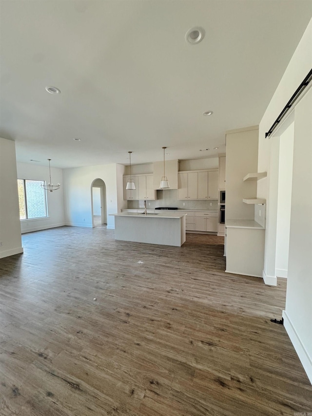 unfurnished living room with sink, a notable chandelier, and dark hardwood / wood-style flooring