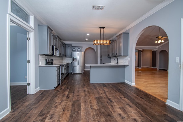 kitchen with decorative backsplash, dark hardwood / wood-style floors, decorative light fixtures, appliances with stainless steel finishes, and ceiling fan with notable chandelier