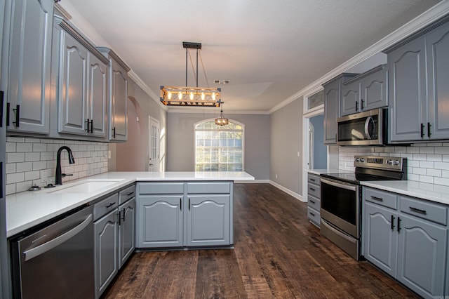 kitchen featuring appliances with stainless steel finishes, sink, kitchen peninsula, pendant lighting, and dark wood-type flooring