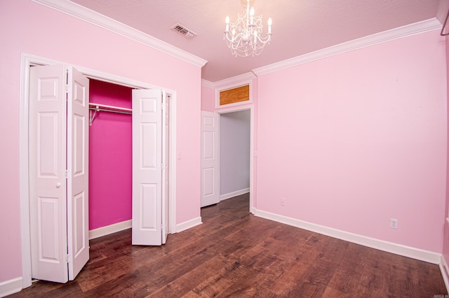 unfurnished bedroom with dark wood-type flooring, a closet, ornamental molding, and a chandelier