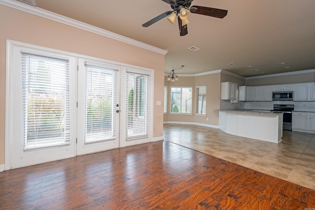 unfurnished living room with crown molding, hardwood / wood-style floors, sink, and ceiling fan with notable chandelier