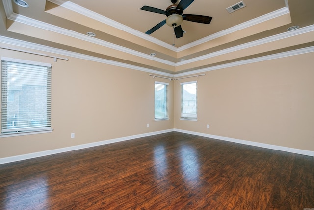 empty room with dark hardwood / wood-style flooring, ornamental molding, and a raised ceiling