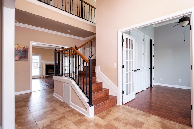 stairs with ornamental molding, hardwood / wood-style floors, ceiling fan, and a brick fireplace