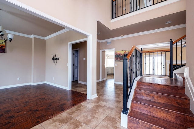 staircase featuring a notable chandelier, crown molding, hardwood / wood-style flooring, and a high ceiling