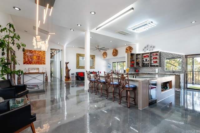 kitchen featuring decorative backsplash, a breakfast bar, light stone countertops, beverage cooler, and ceiling fan