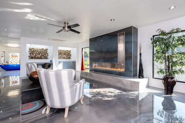 living room with concrete floors, a high end fireplace, a healthy amount of sunlight, and ceiling fan