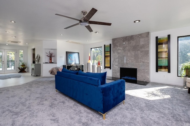 carpeted living room featuring a high end fireplace, plenty of natural light, and ceiling fan