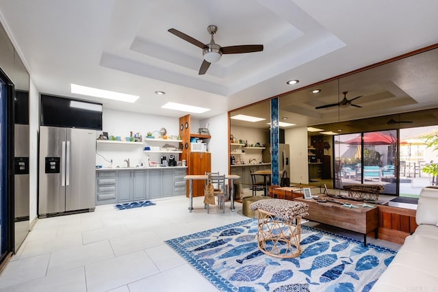 living room with ceiling fan, light tile patterned floors, and a raised ceiling