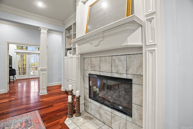 details with hardwood / wood-style flooring, a fireplace, built in features, crown molding, and french doors