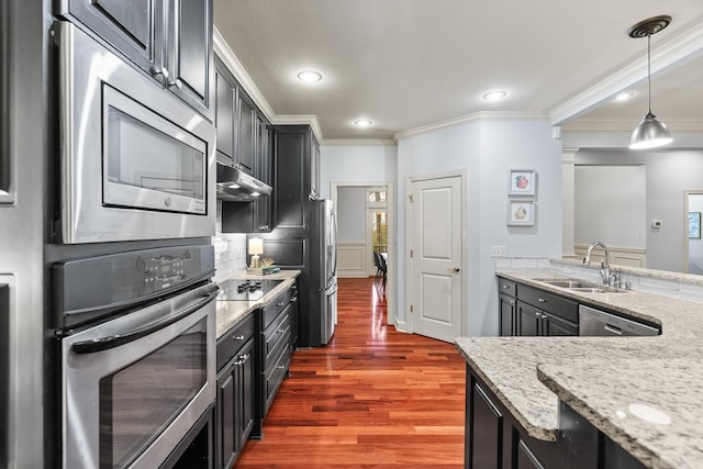 kitchen with dark hardwood / wood-style flooring, appliances with stainless steel finishes, light stone countertops, pendant lighting, and sink