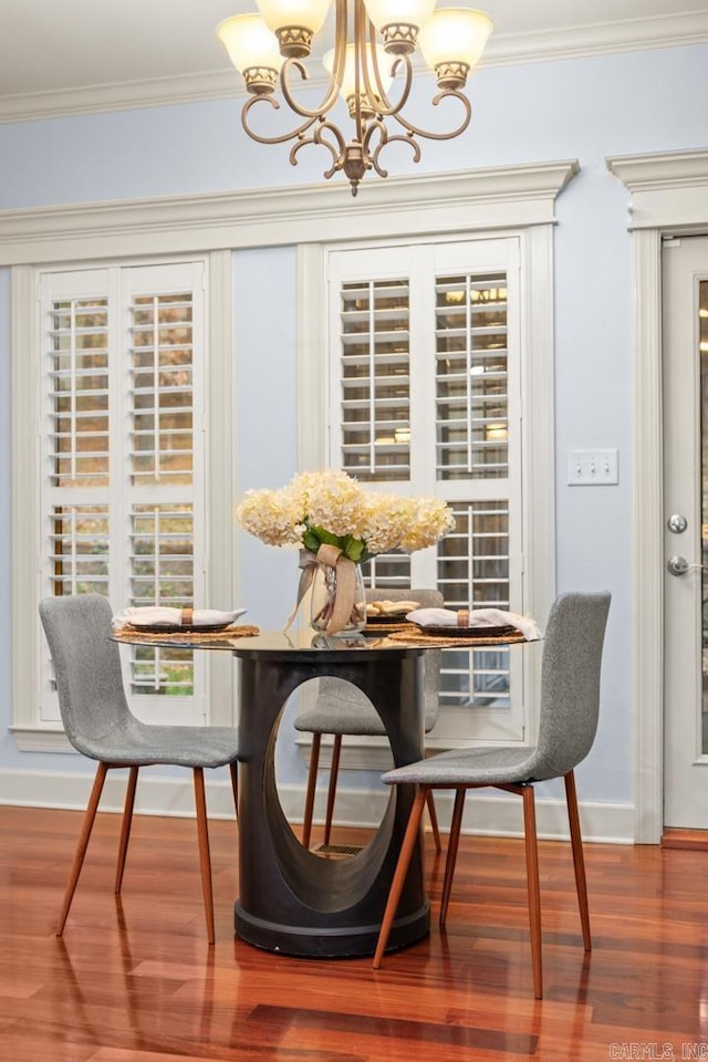 dining area with crown molding, dark hardwood / wood-style floors, and an inviting chandelier