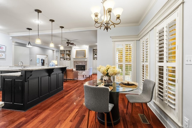 dining area featuring ornamental molding, sink, dark wood-type flooring, and ceiling fan with notable chandelier