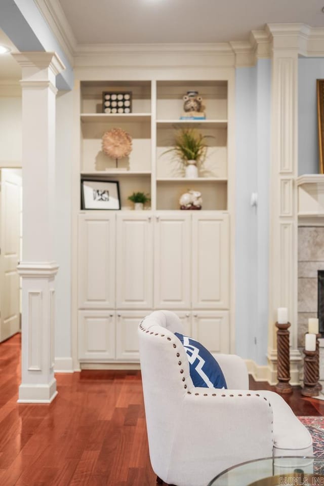 living area featuring built in features, ornamental molding, wood-type flooring, and a tile fireplace