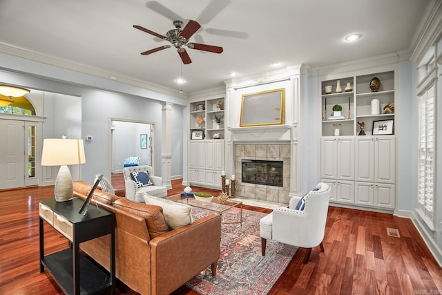 living room with crown molding, decorative columns, a fireplace, and hardwood / wood-style floors