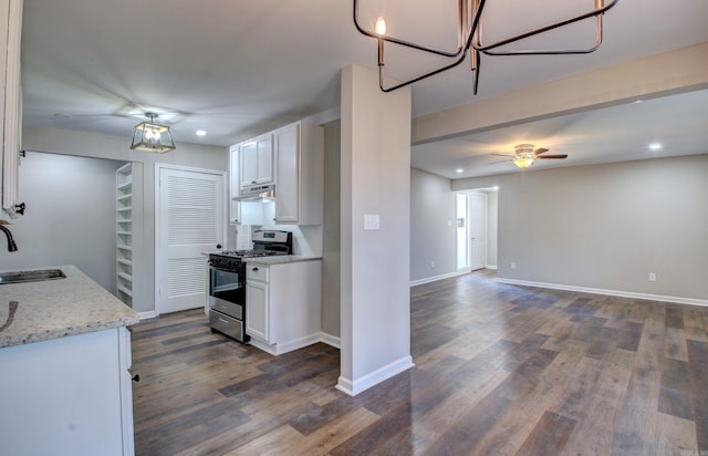 kitchen featuring stainless steel gas range oven, white cabinets, light stone counters, and dark wood-type flooring