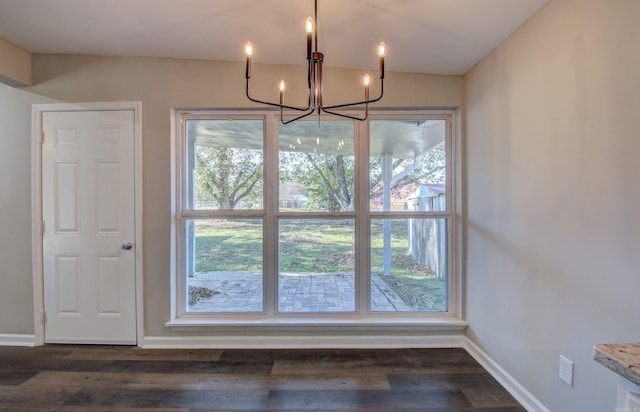 unfurnished dining area with a chandelier and dark hardwood / wood-style floors