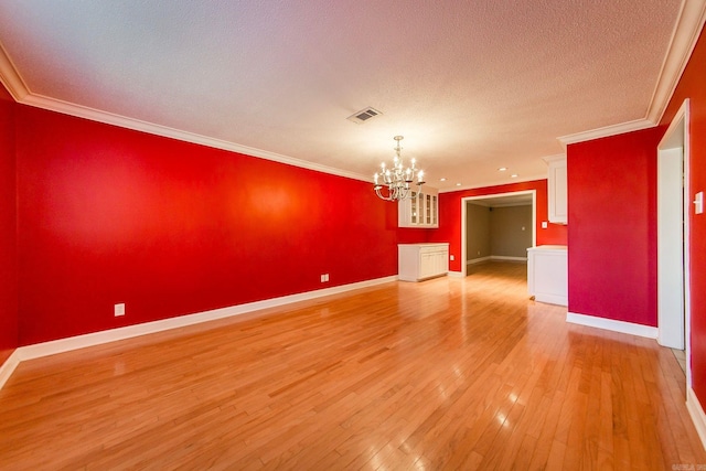 unfurnished room with light hardwood / wood-style flooring, a textured ceiling, an inviting chandelier, and ornamental molding