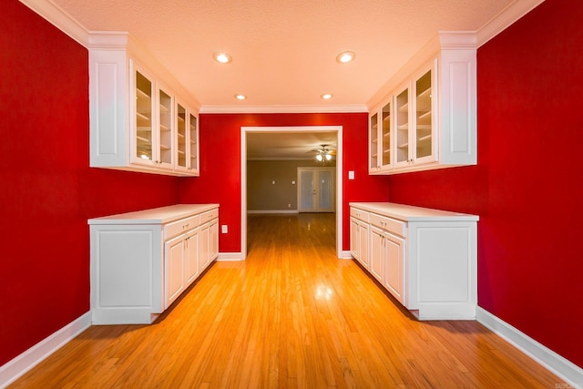 kitchen featuring crown molding, white cabinets, and light hardwood / wood-style flooring