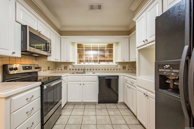 kitchen featuring sink, black appliances, crown molding, light tile patterned flooring, and white cabinets