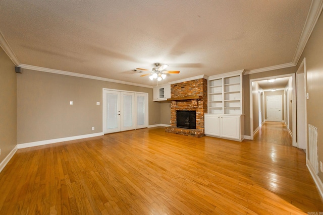 unfurnished living room featuring crown molding, light hardwood / wood-style flooring, a fireplace, and a textured ceiling