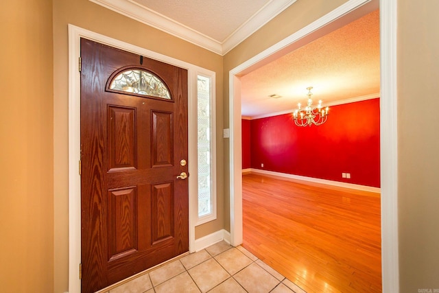 entrance foyer featuring light hardwood / wood-style flooring, a textured ceiling, a chandelier, and crown molding