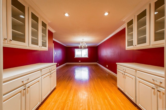 interior space featuring light hardwood / wood-style flooring, a notable chandelier, and crown molding