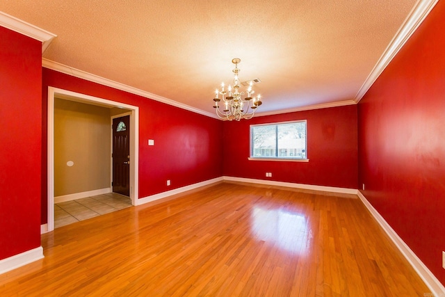 empty room with a notable chandelier, ornamental molding, a textured ceiling, and wood-type flooring