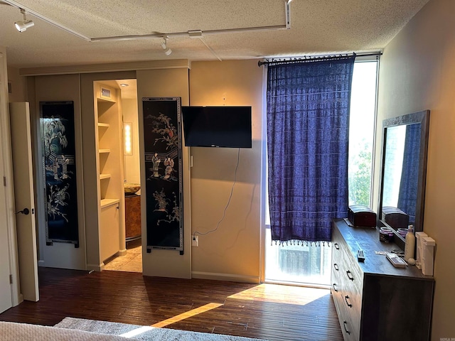 bedroom with rail lighting, a textured ceiling, and light hardwood / wood-style floors