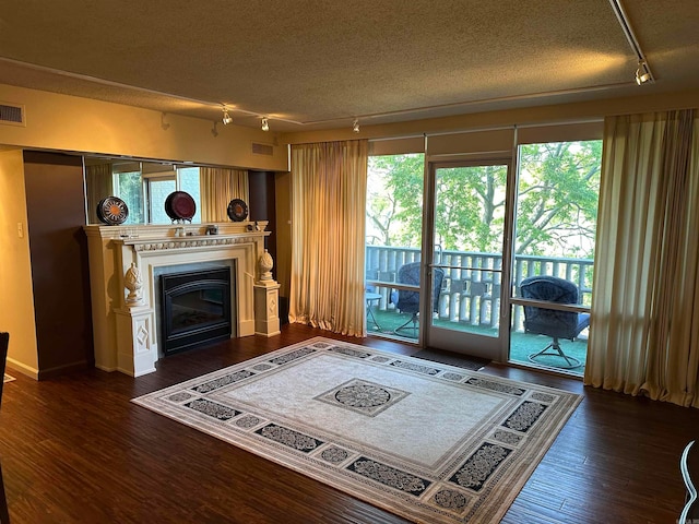 unfurnished living room featuring dark hardwood / wood-style flooring, a textured ceiling, rail lighting, and a wealth of natural light