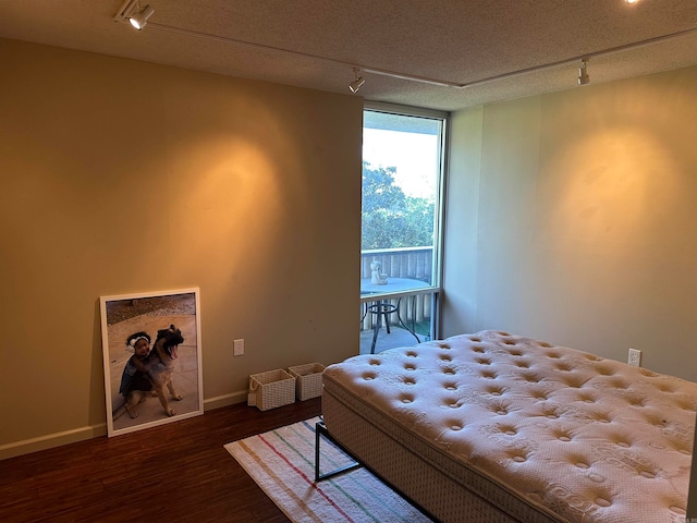 bedroom with dark wood-type flooring, a textured ceiling, and rail lighting