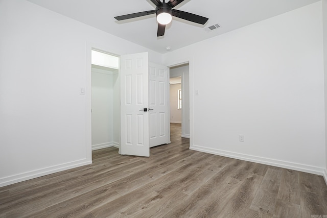 unfurnished bedroom featuring wood-type flooring, a closet, and ceiling fan