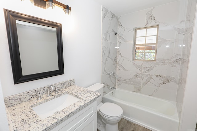 full bathroom with tiled shower / bath, vanity, hardwood / wood-style flooring, and toilet