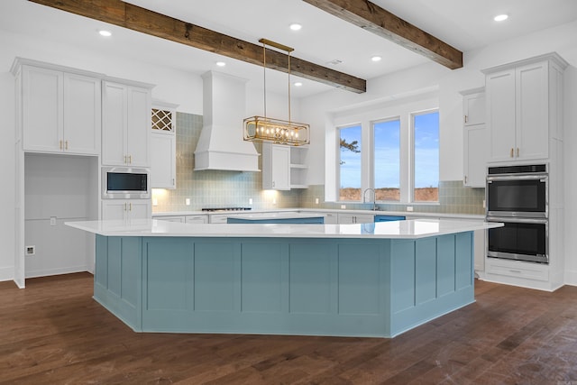 kitchen with white cabinets, appliances with stainless steel finishes, premium range hood, hanging light fixtures, and a large island