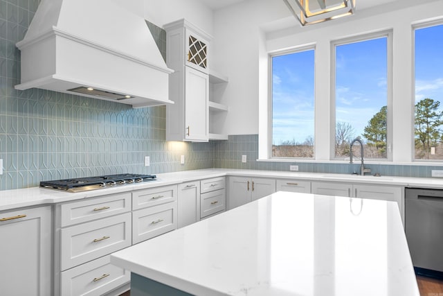 kitchen featuring white cabinetry, custom exhaust hood, stainless steel appliances, backsplash, and sink