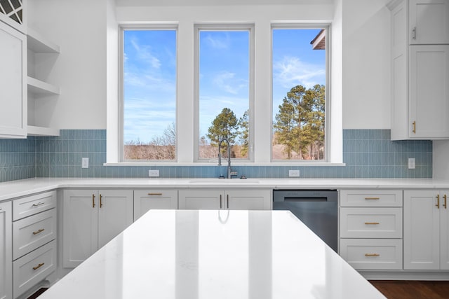 kitchen featuring dishwasher, tasteful backsplash, light stone counters, and sink