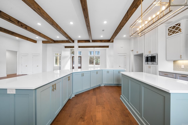 kitchen featuring decorative light fixtures, stainless steel microwave, dark hardwood / wood-style floors, and a large island