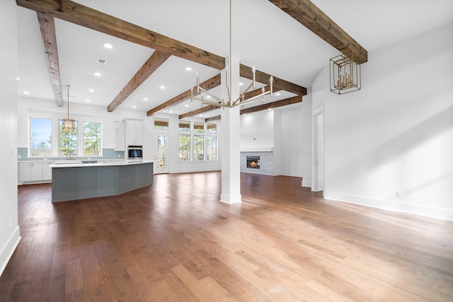 unfurnished living room featuring an inviting chandelier and wood-type flooring