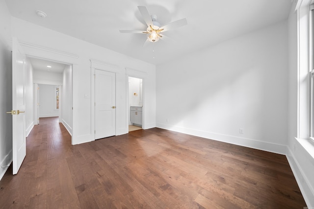 unfurnished bedroom with ceiling fan, dark wood-type flooring, and connected bathroom