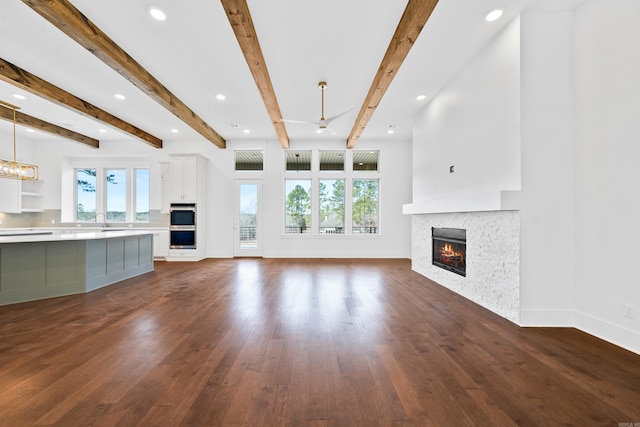 unfurnished living room with beam ceiling, dark hardwood / wood-style flooring, and sink