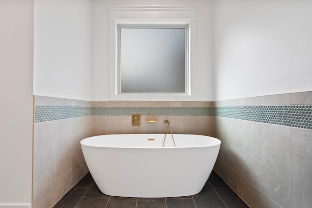 bathroom with tile walls, a bathtub, and tile patterned flooring